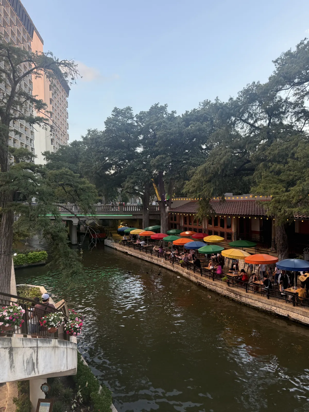 River Walk patios with colorful umbrellas under cypress trees